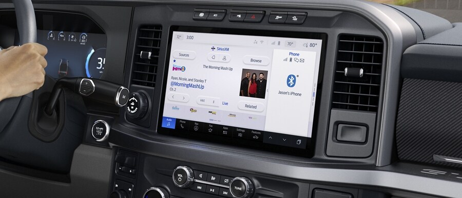 Woman driving with the navigation and music split screen shown on the 12-inch center display