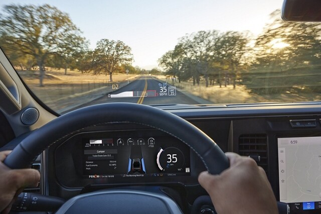 Close-up driver perspective of the digital instrument cluster and available Head-Up Display graphic on the windshield