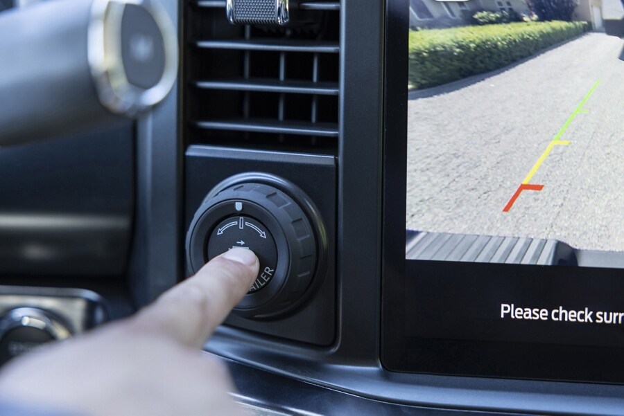 Person pressing the Pro trailer Hitch button with camera view showing on the display screen