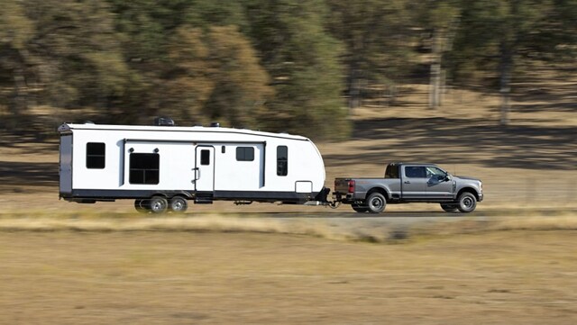 Una Ford Super Duty® F-250® 2023 con Paquete Todo Terreno Tremor remolcando una casa rodante sobre un camino de tierra