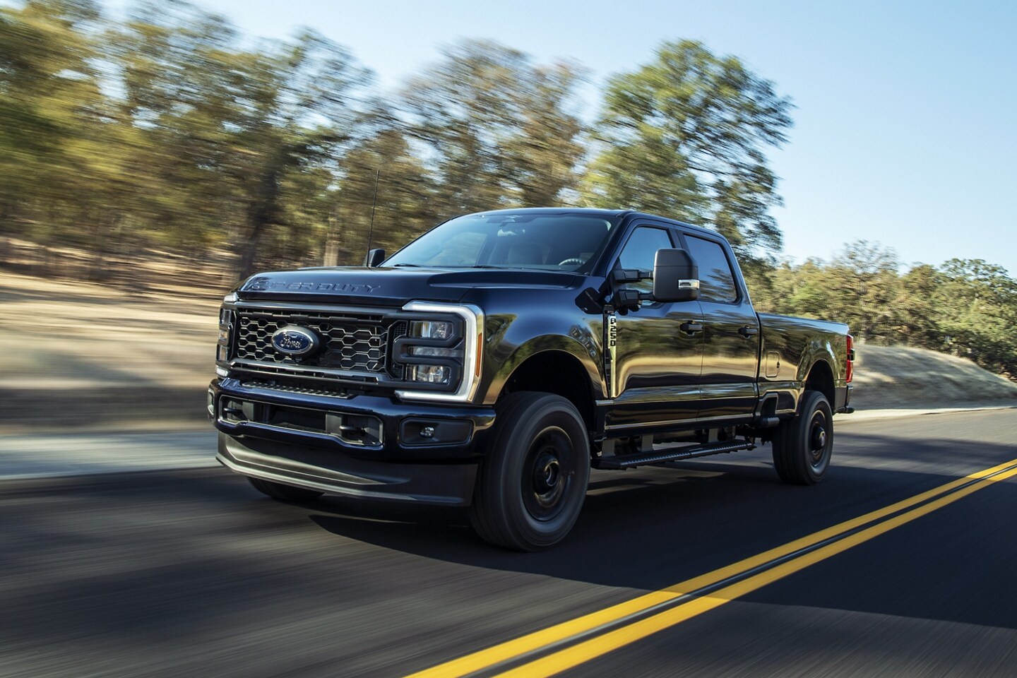 New Black 2023 Ford F-250 Super Duty Contractor Truck driving down a two way street