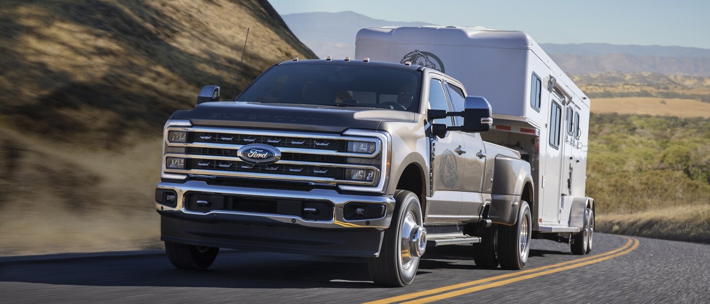 2023 Ford Super Duty® F-350® Lariat towing trailer on road through mountains