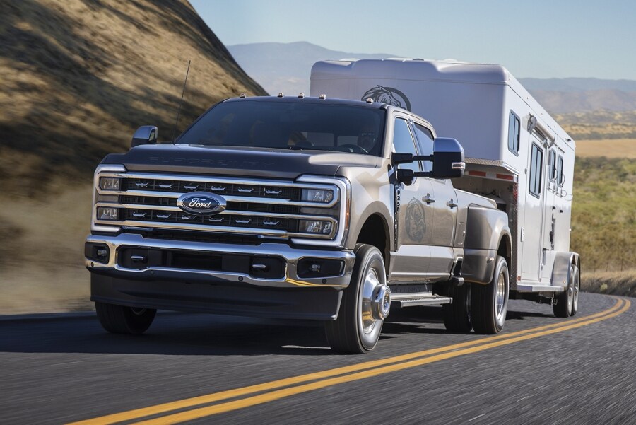 2023 Ford Super Duty® F-350® Lariat towing trailer on road through mountains