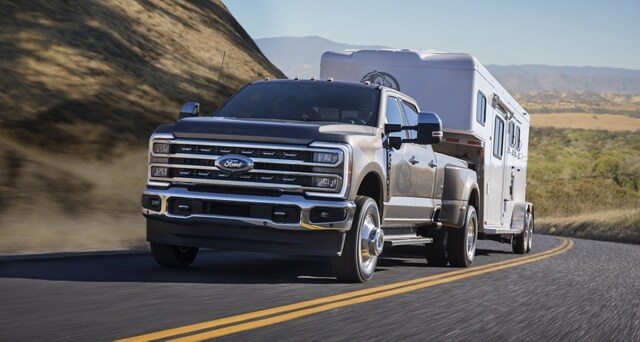 Una Ford Super Duty® F-350® Lariat 2023 remolcando un tráiler por un camino montañoso