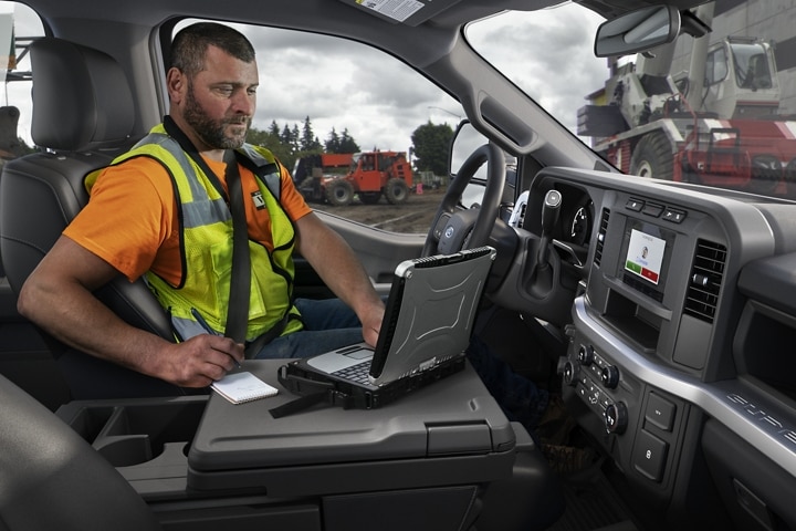 Un hombre trabajando en una laptop dentro de una camioneta Ford Super Duty® F-250® XL 2023