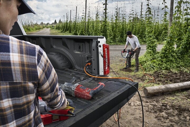 Two workers using the Pro Power Onboard feature on a 2023 Ford Super Duty® pickup