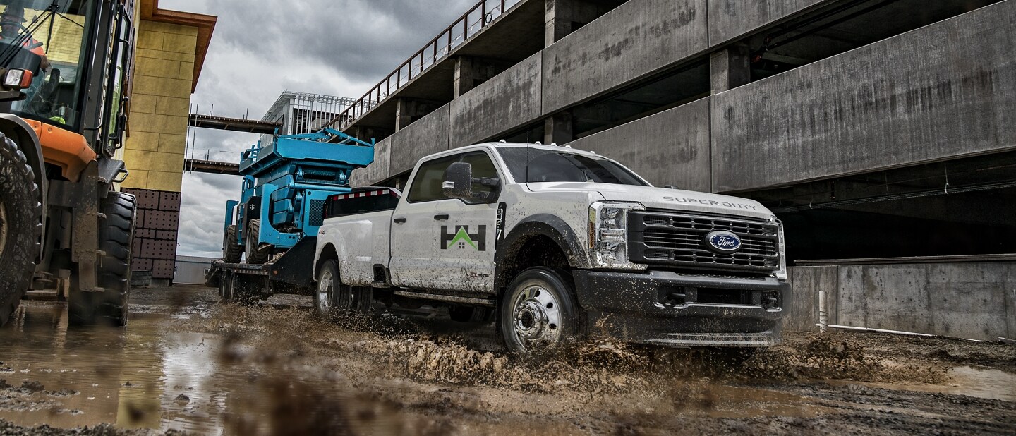 2023 Ford Super Duty® F-450® XL pulling a hydraulic lift through muddy water