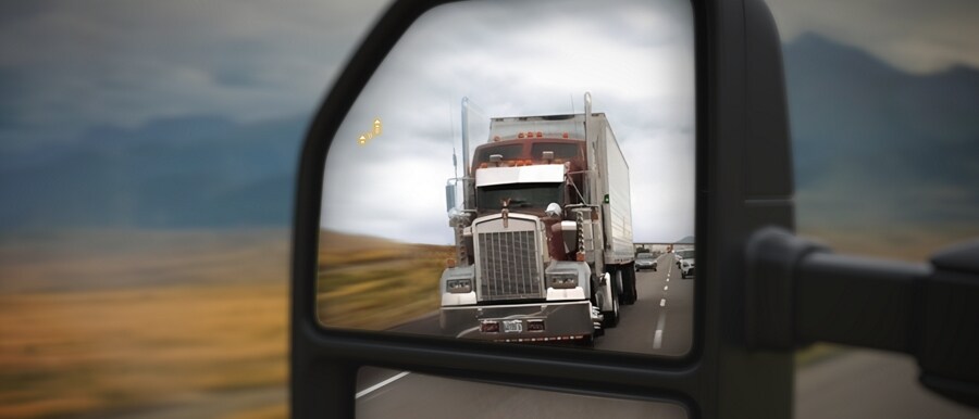 Side mirror of 2023 Ford Super Duty® showing semi truck in blind spot and BLIS® signal activated