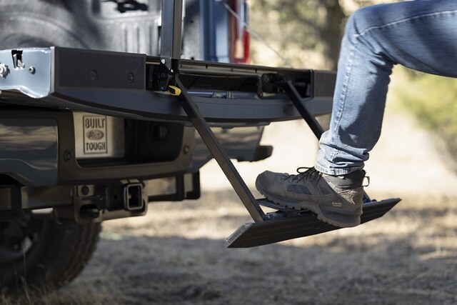 Close-up of a person stepping on the rear tailgate step on a 2023 Ford Super Duty® pickup