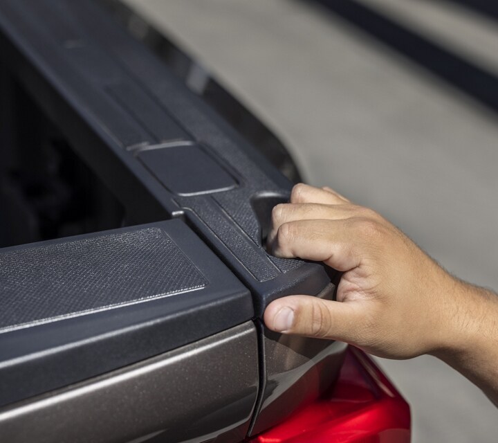 Primer plano de una persona agarrando el espacio para agarrarse de la plataforma de la camioneta en una camioneta Ford Super Duty® 2023