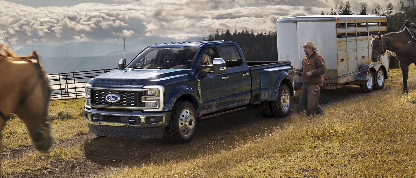 A man riding a horse toward a 2024 Ford Super Duty® F-450® King Ranch® DRW model hitched to a horse trailer