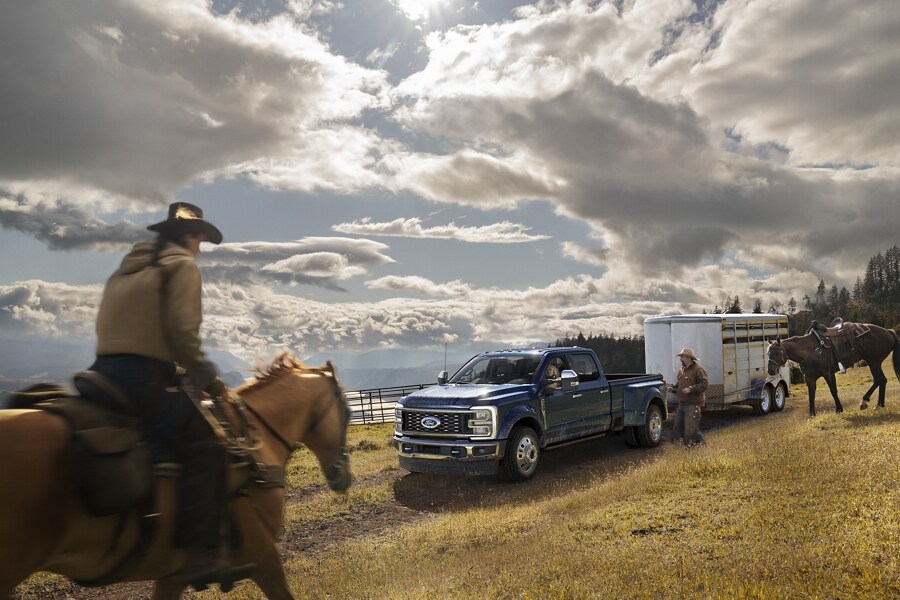 A man riding a horse toward a 2024 Ford Super Duty® F-450® King Ranch® DRW model hitched to a horse trailer