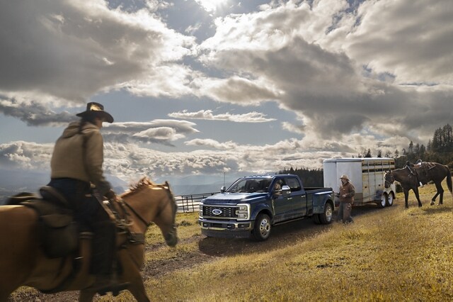 A man riding a horse toward a 2024 Ford Super Duty® F-450® King Ranch® DRW model hitched to a horse trailer