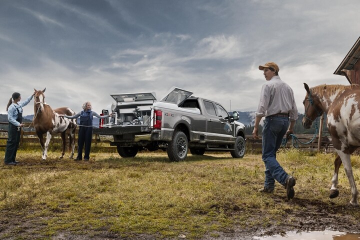 Man walking a horse toward two women standing near a 2024 Ford Super Duty® F-250® Platinum model with the tailgate down
