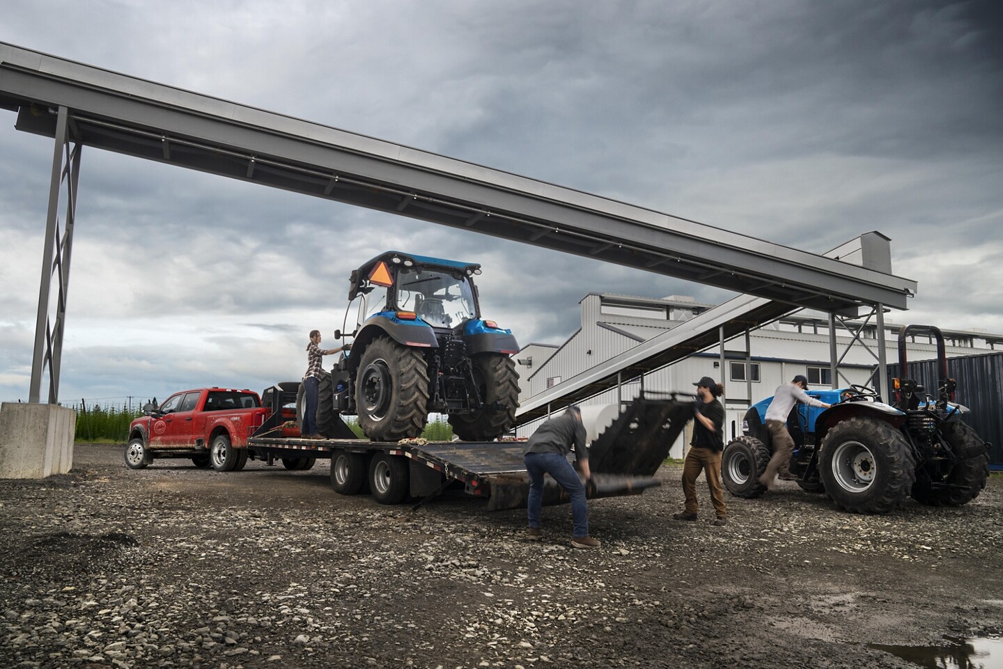 Red 2024 Ford F-250 Super Duty with large blue tractor being loaded on it