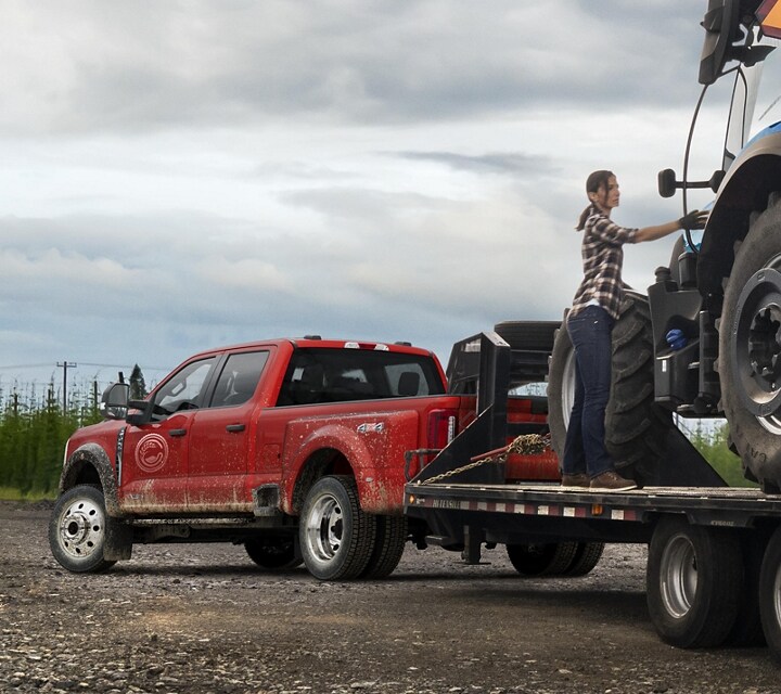Workers loading a tracker onto a trailer hitched to a 2024 Super Duty® F-450® XL in Race Red