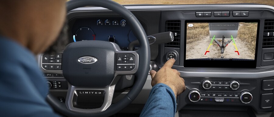 A person pushing the pro trailer backup assist knob with camera image displayed on screen in a 2024 Ford Super Duty® pickup