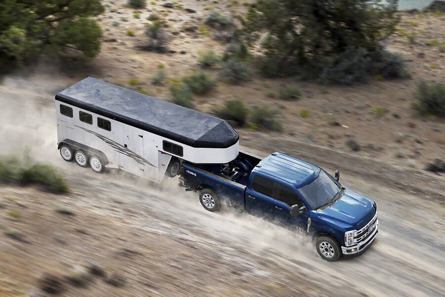 2024 Ford Super Duty® F-350® XLT in Antimatter Blue pulling a trailer on a dirt road