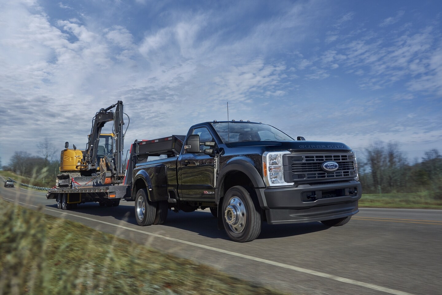 Black 2024 Ford F-350 Super Duty transporting a yellow escavator