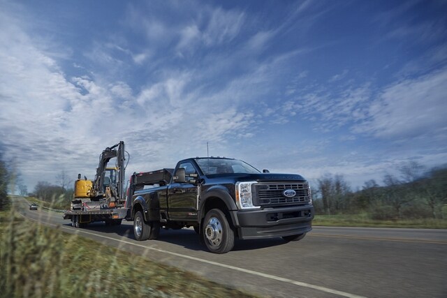 2024 Ford Super Duty® F-450® XL in Agate Black hitched to a trailer carrying a backhoe