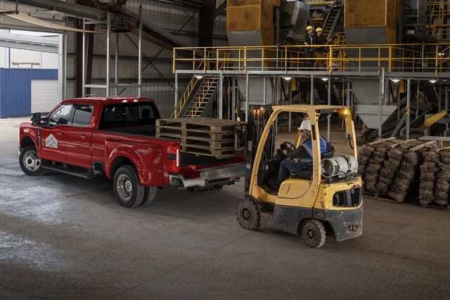 Man watching a fork lift load cargo into the back of a 2025 Ford Super Duty® F-350® LARIAT® pickup