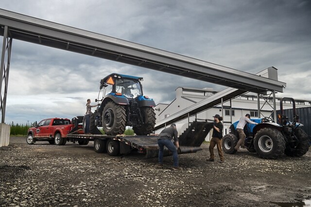 People loading a large tractor onto a trailer hitched to a 2025 Ford Super Duty® F-450® XL DRW truck in Rapid Red