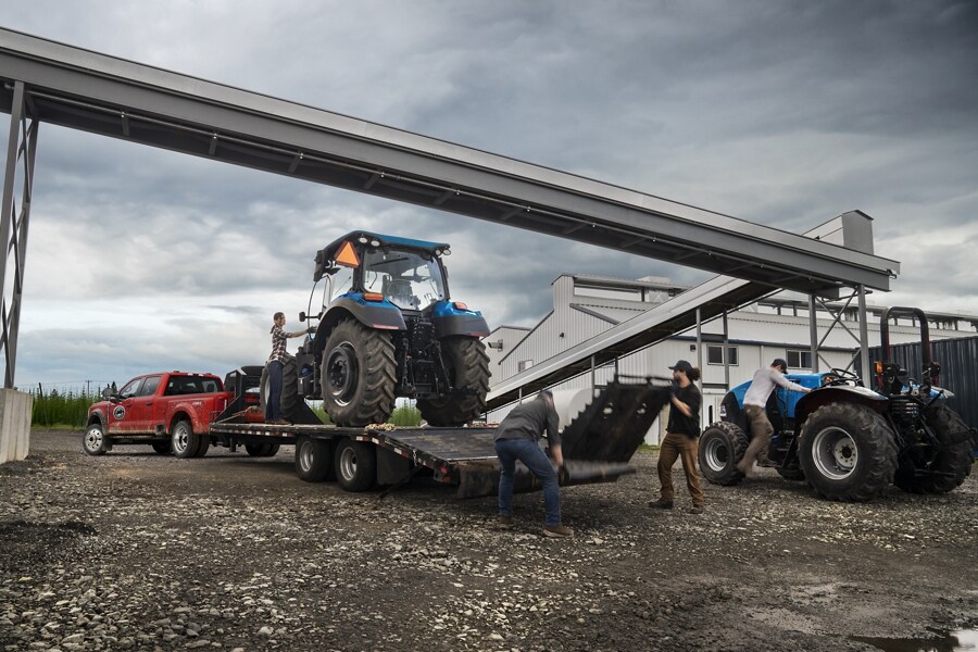 People loading a large tractor onto a trailer hitched to a 2025 Ford Super Duty® F-450® XL pickup