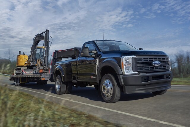 2025 Ford Super Duty® F-450® XL pickup in Agate Black pulling a backhoe on a trailer