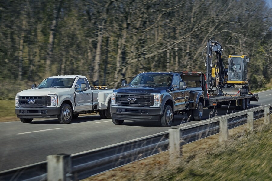 2025 Ford Super Duty® F-350® XL DRW in Oxford White and F-450® XL DRW in Antimatter Blue being driven side by side on a paved road