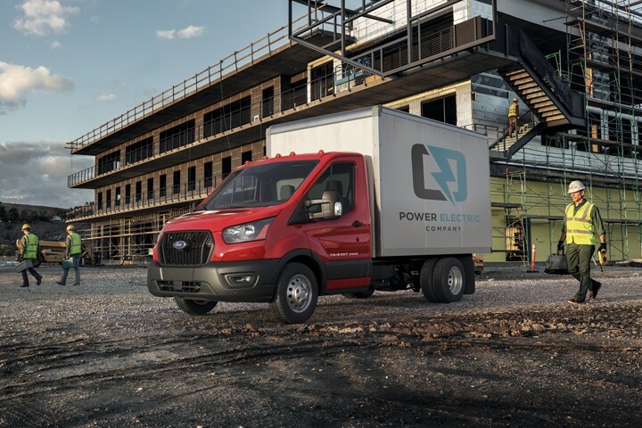 A 2023 Ford Transit® Chassis Cab on a worksite with workers in the background