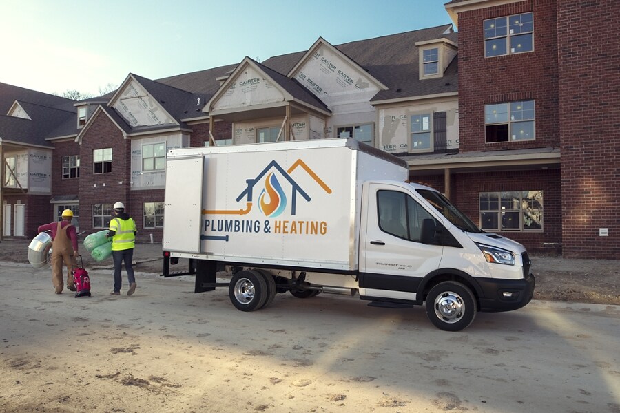 Una Ford Transit® Chassis Cab 2023 estacionada en una obra en construcción con dos trabajadores acercándose