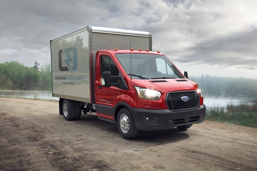 Una Ford Transit® Chassis Cab 2023 en un camino de tierra cerca de un lago