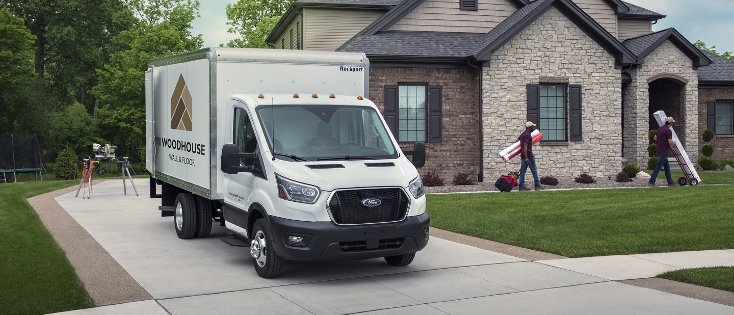 A 2023 Ford Transit® Chassis Cab is parked at a house with workers unloading