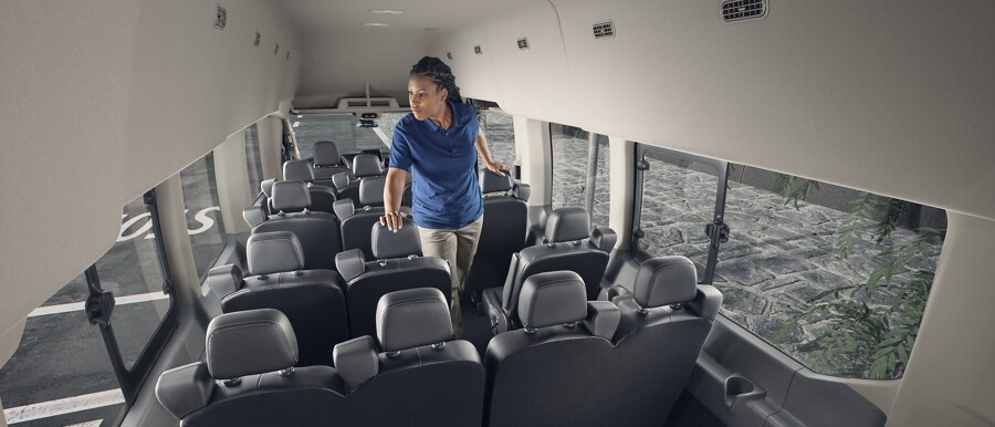 Una mujer parada en el interior de una van Ford Transit® 2023 con 15 asientos.