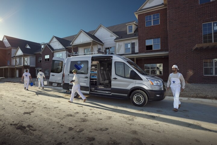Un equipo de trabajo descargando de una van Ford Transit® 2023 cerca de un sitio de construcción