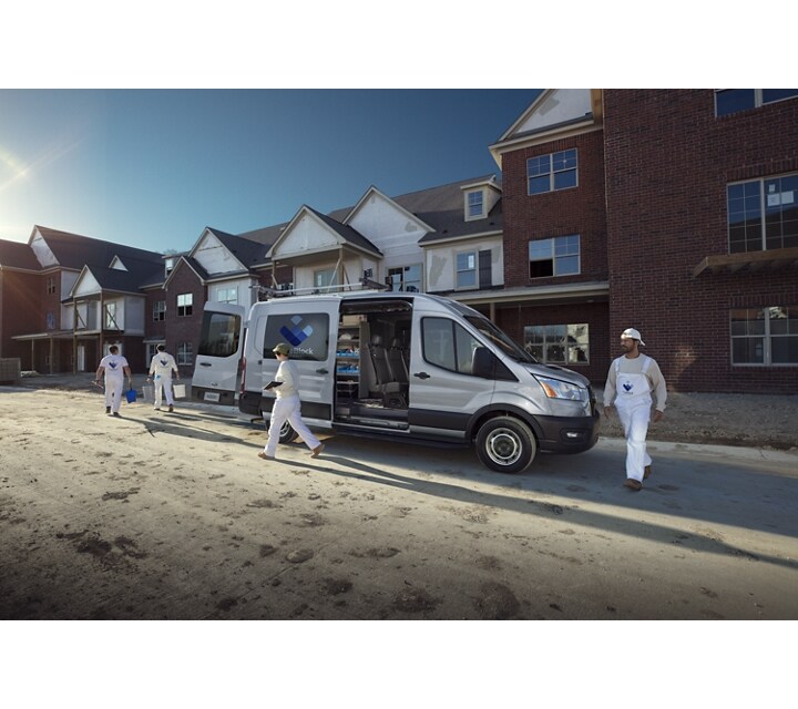 Un equipo de trabajo descargando de una van Ford Transit® 2023 cerca de un sitio de construcción