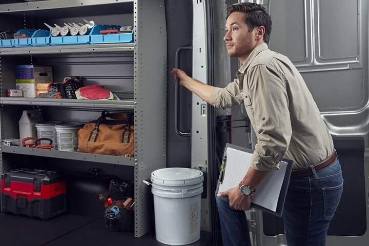 A worker getting into the back of a 2023 Ford Transit® van using the D-pillar assist handle