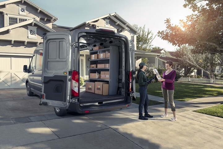 A work crew unloading a 2023 Ford Transit® van near a suburban home