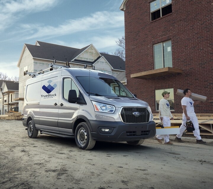 Two workers walking away from a 2023 Ford Transit® van in Ingot Silver at a construction site