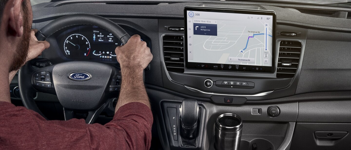 A man behind the wheel of a 2023 Ford Transit® van using the navigation system