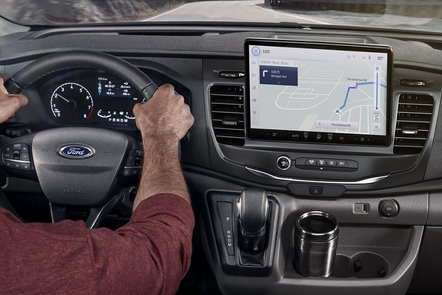A man behind the wheel of a 2023 Ford Transit® van using the navigation system