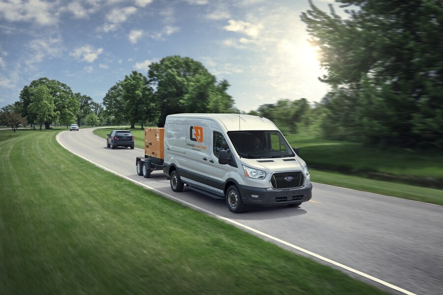 Una van Ford Transit® 2023 bajando por un camino remolcando un tráiler