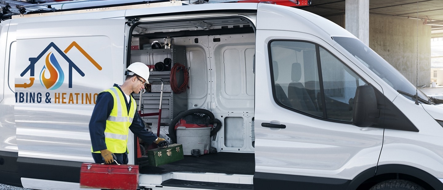 Man unloading tools from a 2024 Ford Transit® van with power-sliding door