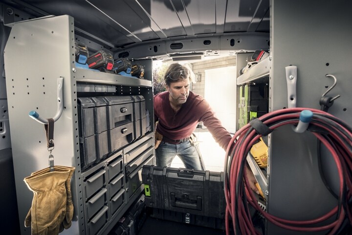 Zona de carga de una Ford Transit Connect Cargo Van 2023 mostrando un hombre con estantes mejorados no originales