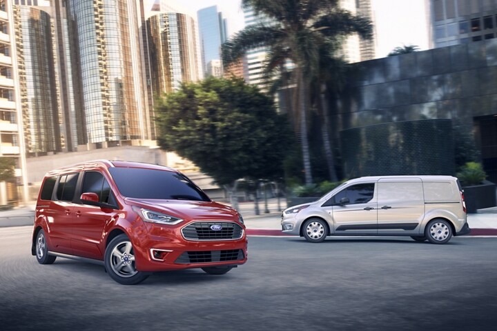 A 2023 Ford Transit Connect Passenger Wagon in Race Red and a Transit Connect Cargo Van in Silver on the street