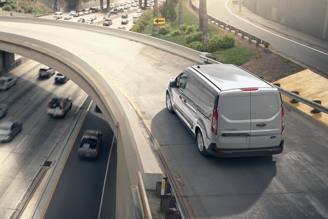 2023 Ford Transit Connect Cargo Van in Silver being driven on a curved highway ramp