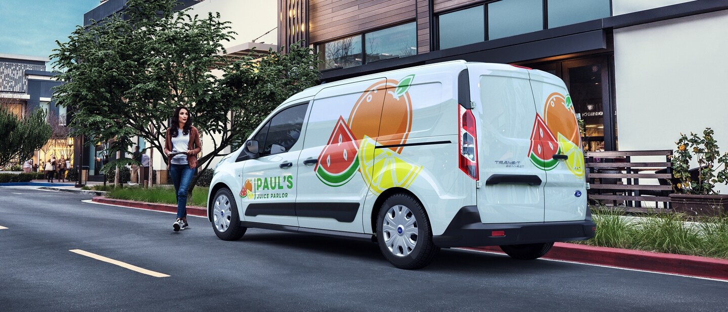 Una Ford Transit Connect Cargo Van 2023 con gráficos comerciales estacionada en una calle urbana