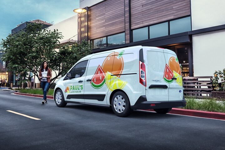 Una Ford Transit Connect Cargo Van 2023 con gráficos comerciales estacionada en una calle urbana