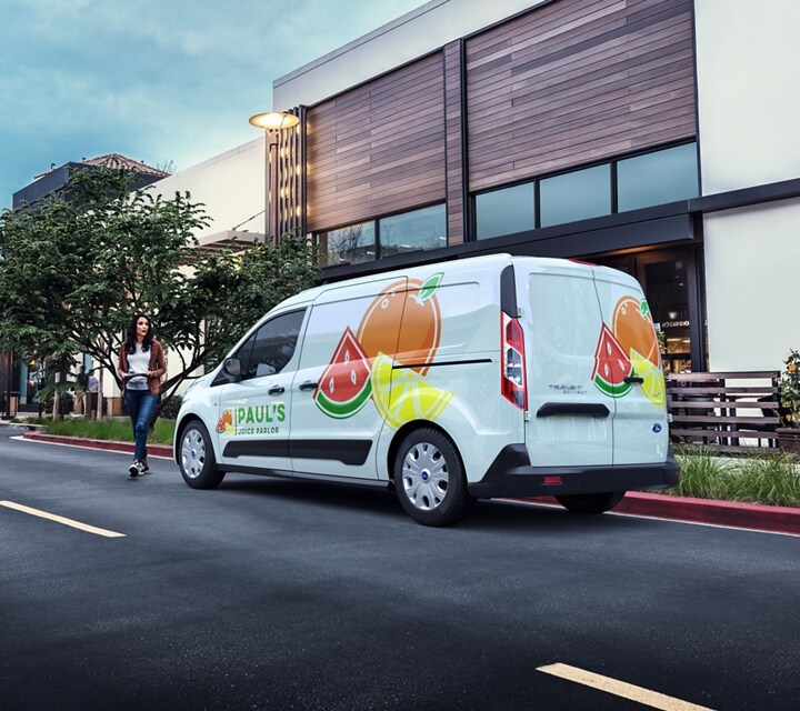 Una Ford Transit Connect Cargo Van 2023 con gráficos comerciales estacionada en una calle urbana