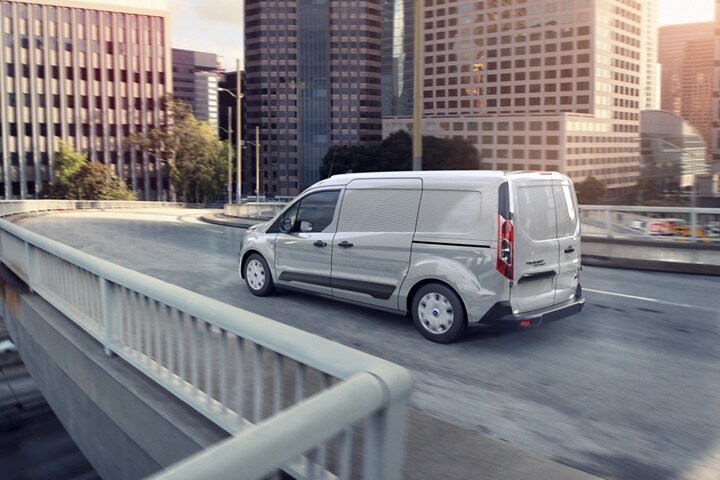 Una Ford Transit Connect Cargo Van 2023 en Silver andando por una calle de ciudad